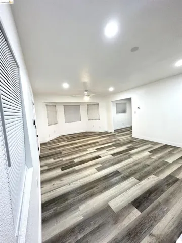 Spacious room featuring wood-finish flooring, recessed lighting, and a ceiling fan