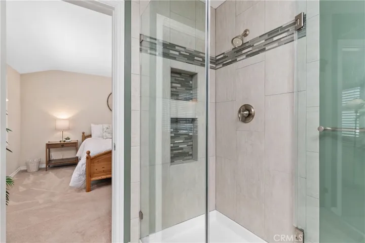 Remodeled Primary Bath features an attractive custom tile design and seamless glass enclosure!