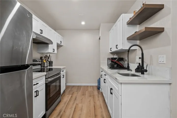 Fully renovated kitchen featuring crisp white shaker cabinetry, quartz countertops, stainless steel appliances, and a modern black pull-down faucet.