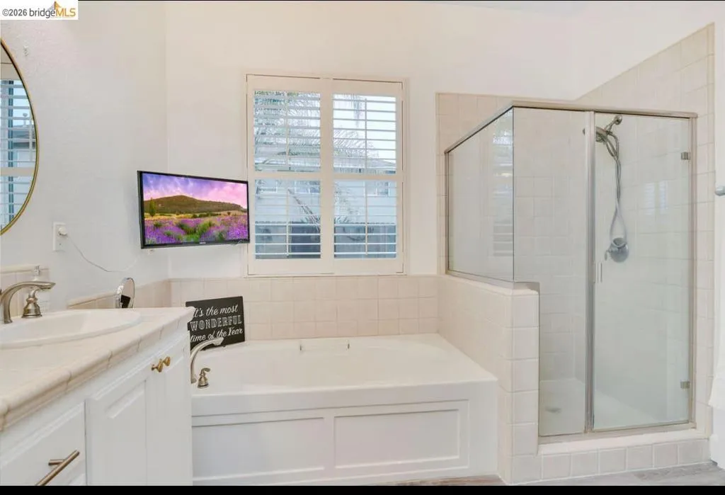 Full bath with a bath, vanity, and a stall shower