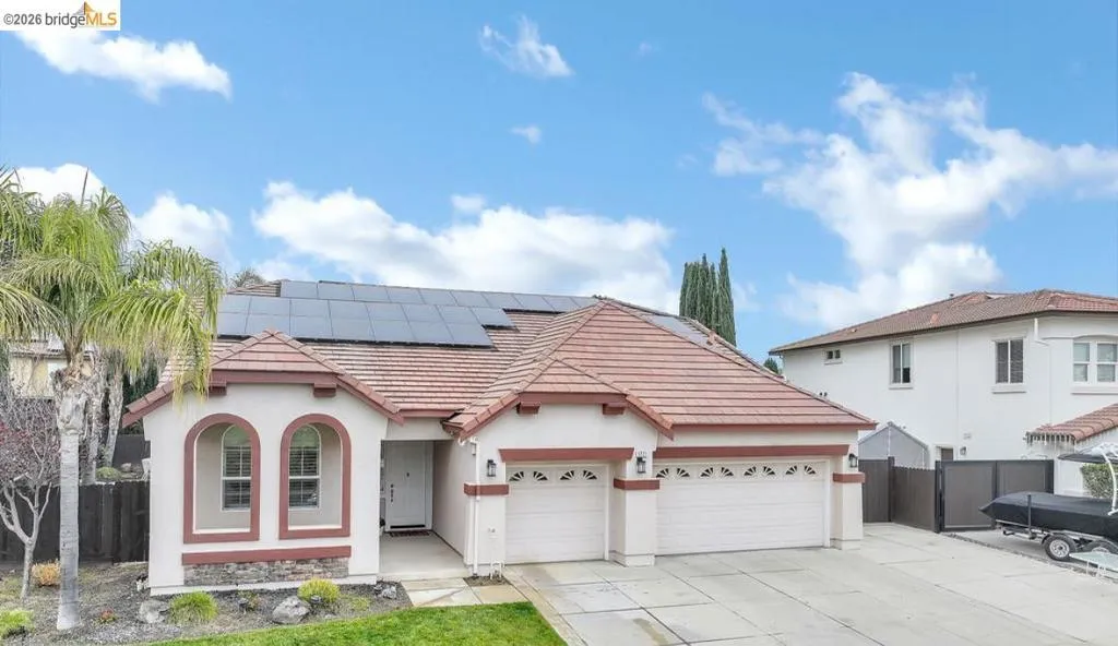 View of front of house with a tile roof, roof mounted solar panels, driveway, stucco siding, and a garage