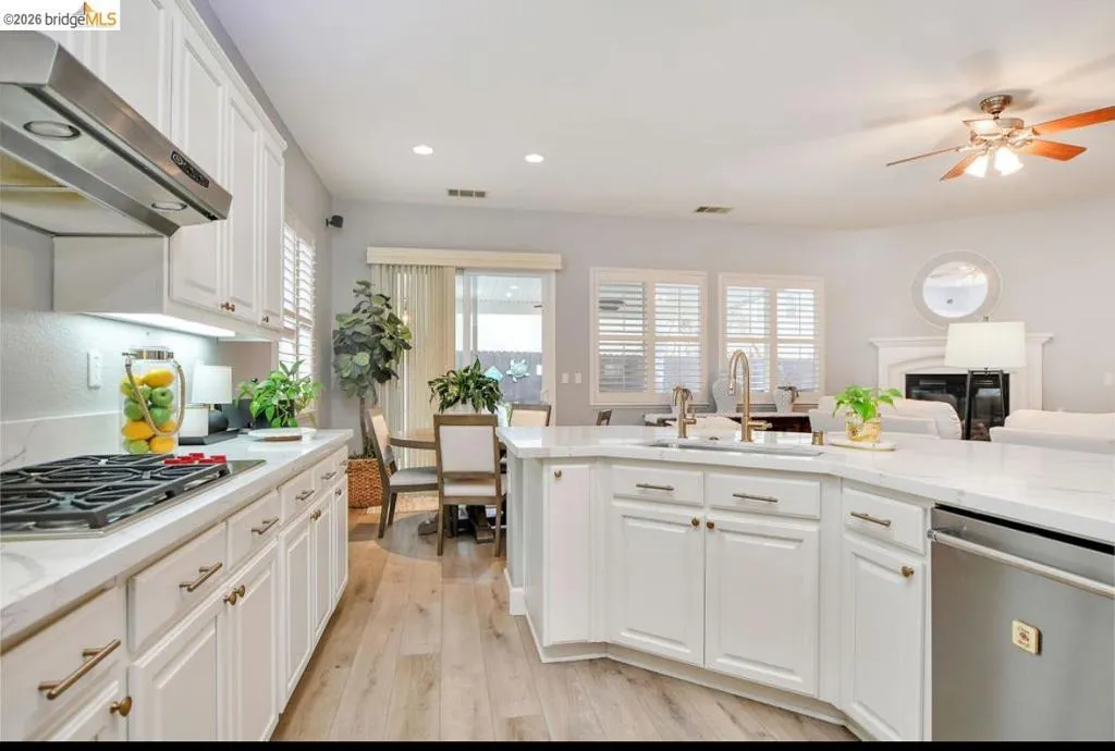 Kitchen with white cabinetry, stainless steel appliances, wall chimney range hood, light stone counters, and recessed lighting