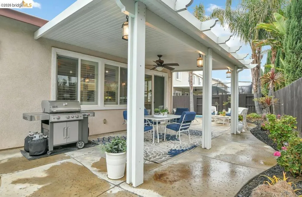 Fenced backyard with a patio, a ceiling fan, grilling area, and outdoor dining area
