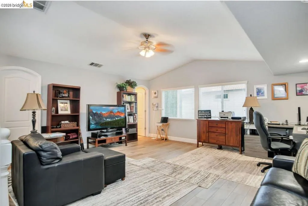 Living room featuring an office area, wood finished floors, lofted ceiling, and a ceiling fan