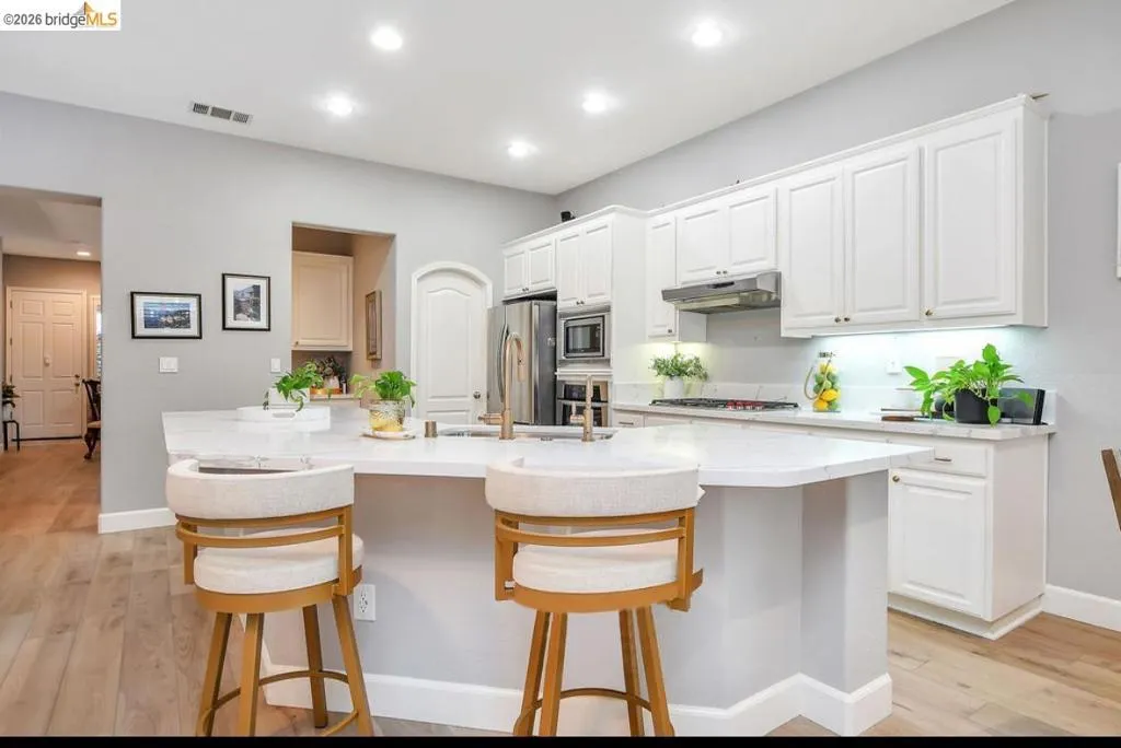 Kitchen with white cabinetry, light wood-type flooring, a kitchen breakfast bar, and recessed lighting