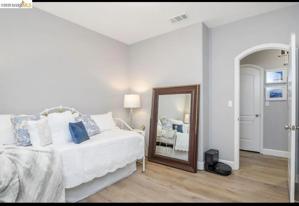 Bedroom featuring arched walkways and light wood-style flooring