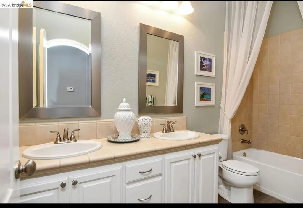 Full bathroom with double vanity and shower / bathtub combination with curtain