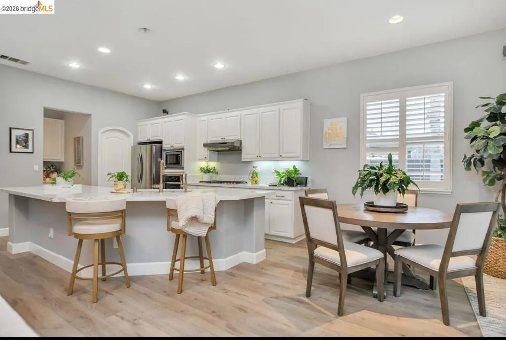 Kitchen featuring white cabinets, recessed lighting, a kitchen breakfast bar, a spacious island, and light stone countertops