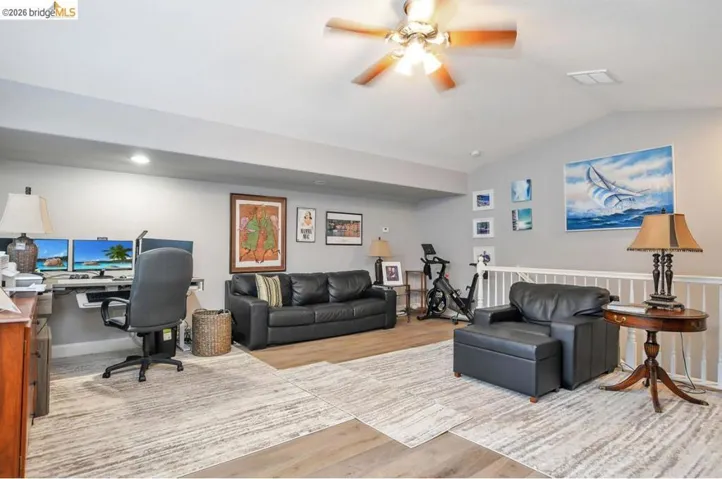 Office space featuring light wood-style floors, a ceiling fan, and vaulted ceiling