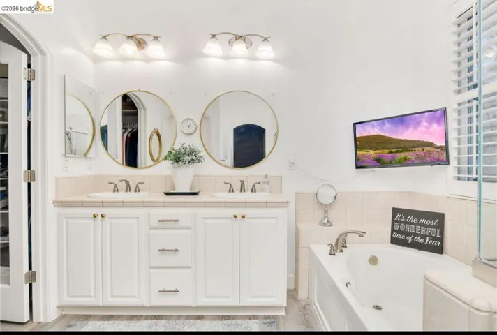 Full bathroom featuring a spacious closet, double vanity, and a garden tub