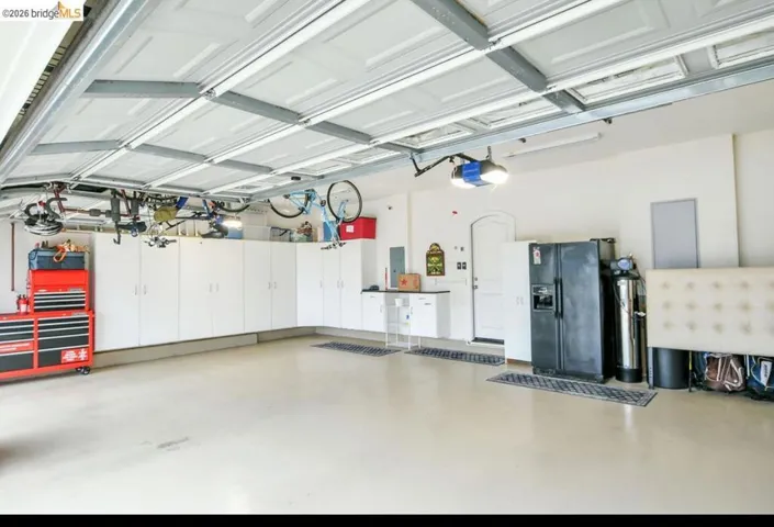 Garage with black fridge, electric panel, and a garage door opener