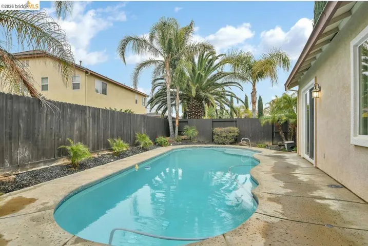 View of swimming pool with a fenced backyard and a patio