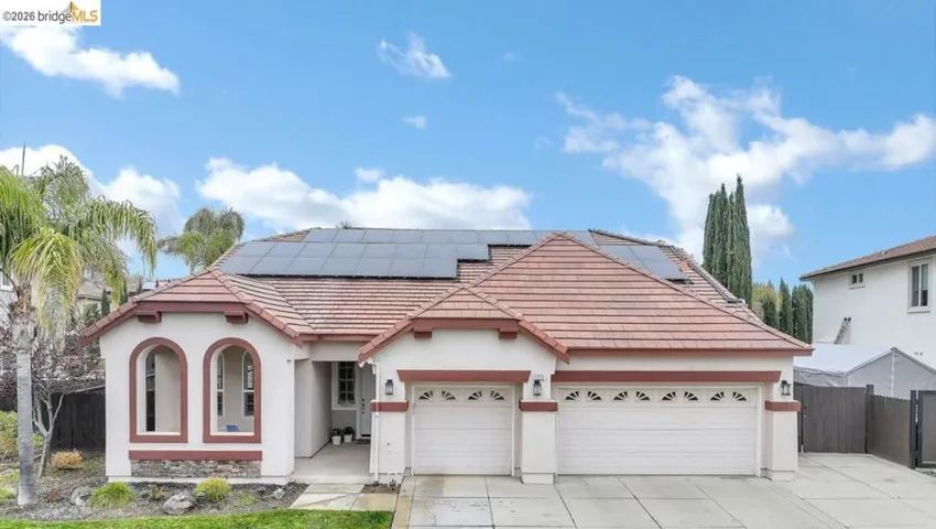 View of front of home with stucco siding, roof mounted solar panels, concrete driveway, an attached garage, and a tile roof