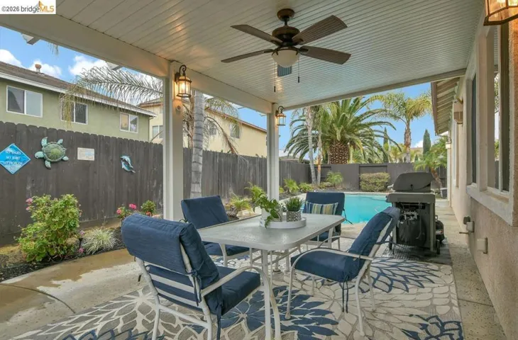 Fenced backyard featuring a patio, a ceiling fan, outdoor dining area, and grilling area