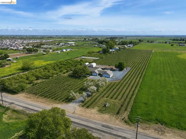 Expansive rural property featuring multiple cultivated fields, a primary residence with an attached garage, and additional outbuildings