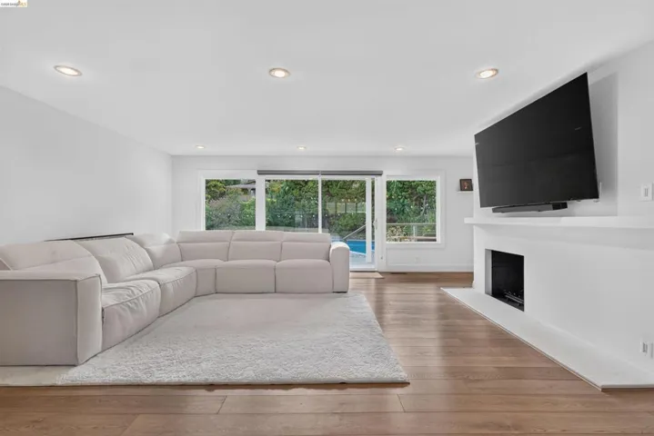 Living area featuring wood-finish flooring, recessed lighting, and a white modern fireplace with an inset firebox