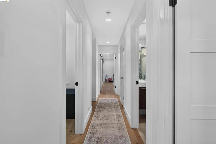 Hallway featuring wood-finish flooring, recessed lighting, white trim, and white doors with matte black hardware