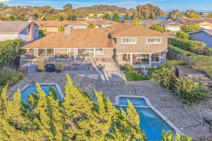 Rear exterior showcasing dual-level decking, an in-ground swimming pool, and a gravel-patterned patio