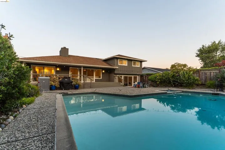 Expansive in-ground swimming pool with surrounding aggregate concrete patio and walkway