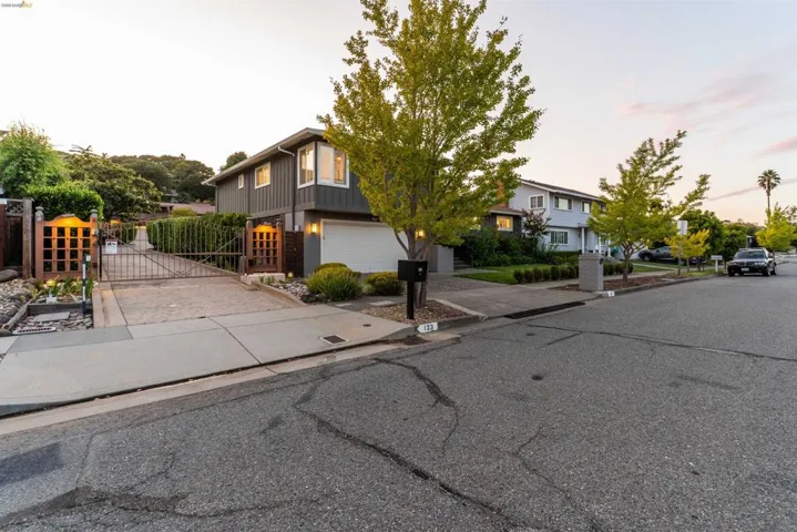 Gated driveway entrance featuring decorative wooden privacy panels, iron gates, and an integrated garage door