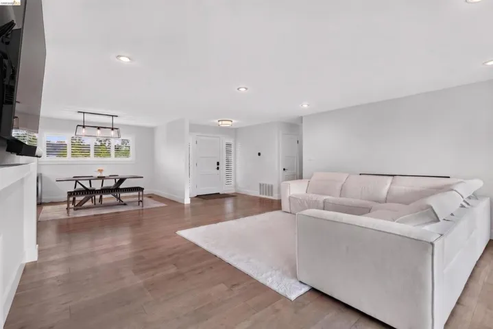Hardwood-finish flooring throughout, recessed ceiling lighting, and a front entry door with side louvered panels
