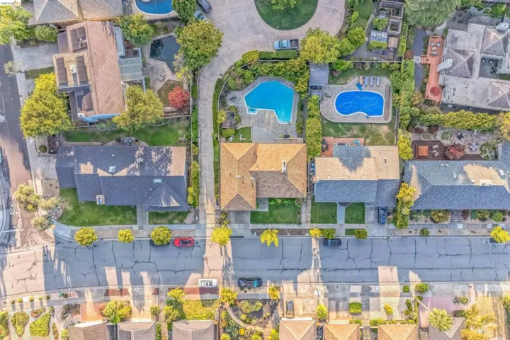 Aerial perspective showcasing a residential neighborhood with properties featuring swimming pools and mature landscaping
