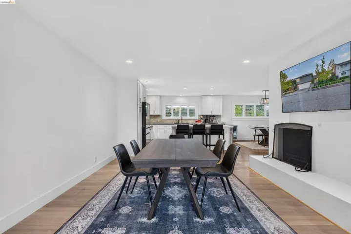 Open-concept living area featuring wood-finish flooring, recessed lighting, and a modern fireplace