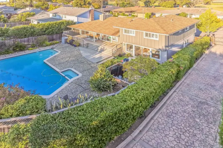 Spacious split-level residence featuring a large geometric swimming pool with an integrated spa, extensive stamped concrete patio, and a multi-level wooden deck