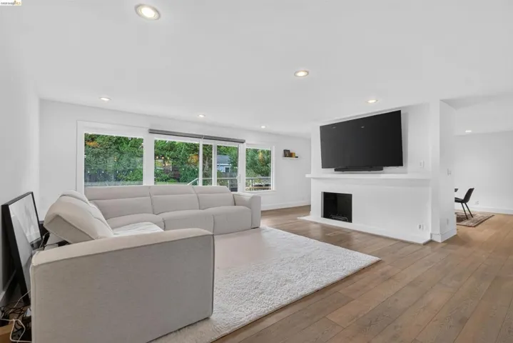 Open concept living space featuring wood-finish flooring, recessed lighting, and a modern fireplace with a mantel