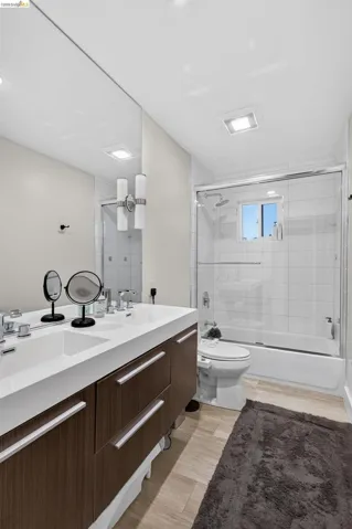 Bathroom featuring a dual-sink vanity with wood-finish cabinetry and a single-slab countertop