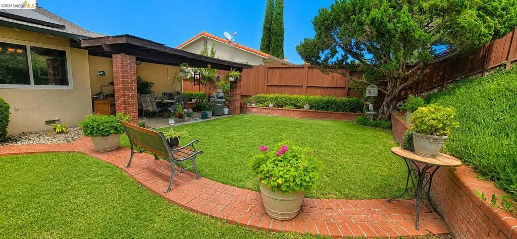 Expansive backyard featuring a lush lawn and a brick paver pathway