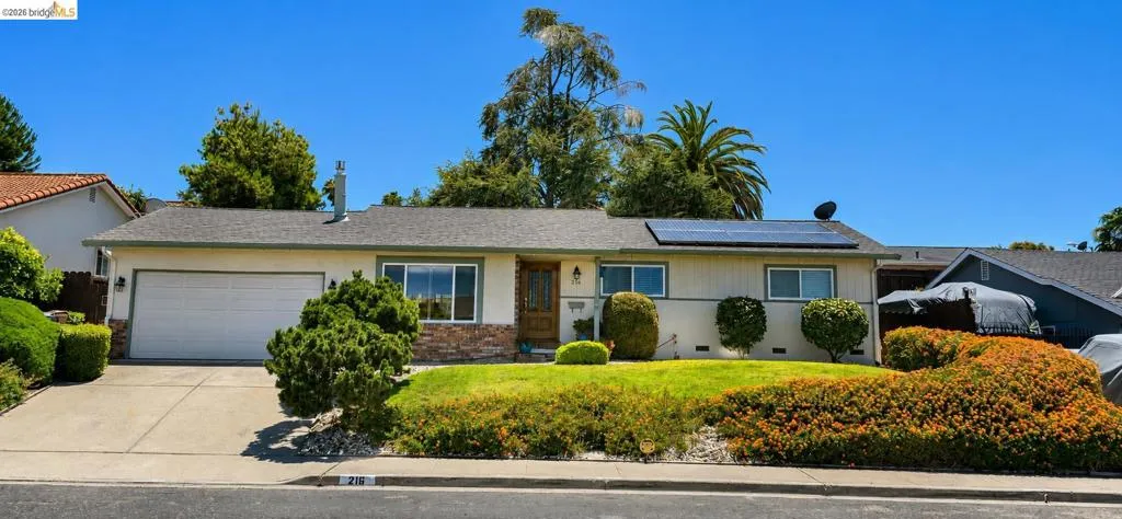 Ranch-style exterior with a two-car garage, solar panels, and a wood entry door