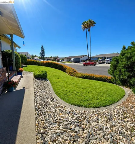 Manicured front yard with a lush lawn, decorative rock landscaping, and a concrete pathway