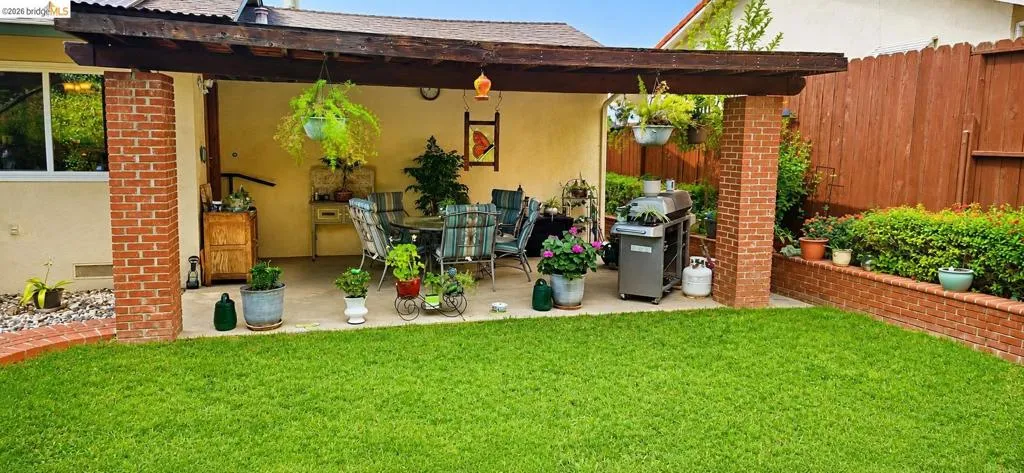 Expansive backyard featuring a lush lawn and a covered patio area