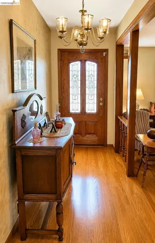 Warm wood-finish flooring complements the detailed wood entry door featuring decorative glass