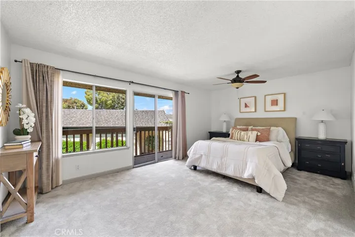 Large master suite with mirrored walk-in closet, sliding glass doors that open to a balcony that over looks the greenbelt and pool