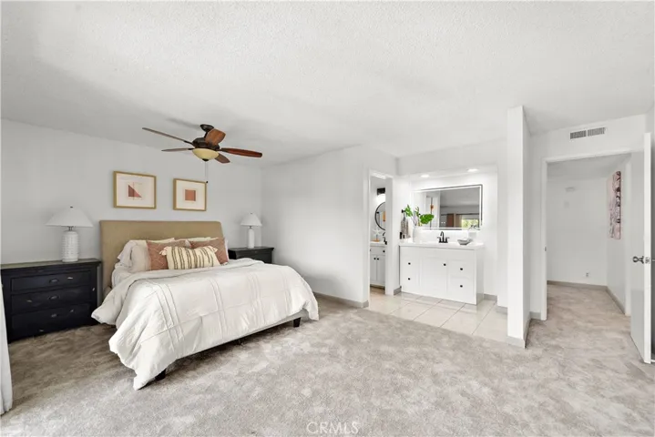 Large master suite with mirrored walk-in closet, sliding glass doors that open to a balcony that over looks the greenbelt and pool and a beautiful remodeled ensuite bathroom with two quartz vanities with newer light fixtures, and a walk-in shower with sitting bench, shampoo niche, designer tile surround and barndoor style clear glass enclosure