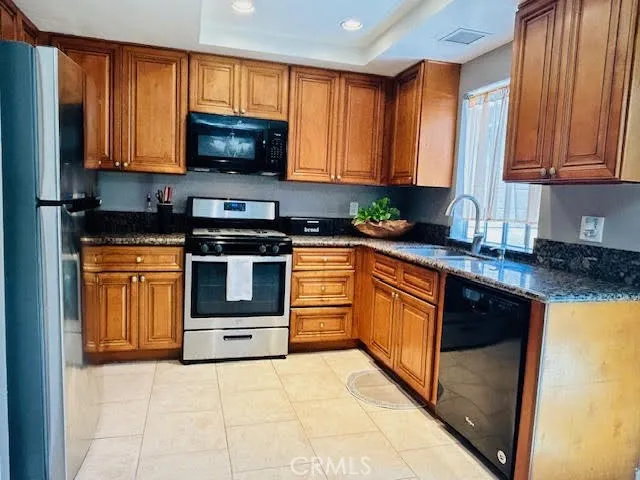 The bright, open kitchen is beautifully appointed with recessed lighting, tile flooring, granite countertops, and a stainless steel refrigerator and range.