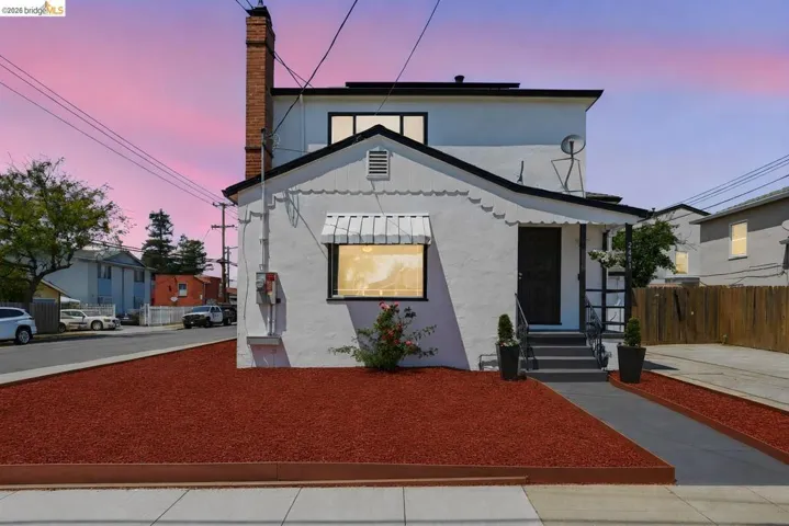 White stucco exterior with black trim, a brick chimney, and a front entry with steps