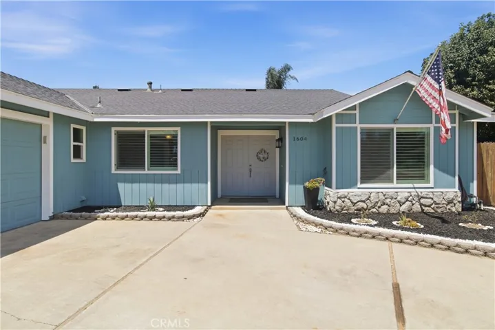 Blue ranch style home with large driveway and basketball hoop