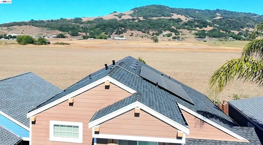 New Roof, Rear View & Paid Solar ... Showcasing the newer composition shingle roof with paid solar and breathtaking rear views of open fields and rolling hills, offering exceptional privacy and a picturesque backdrop.