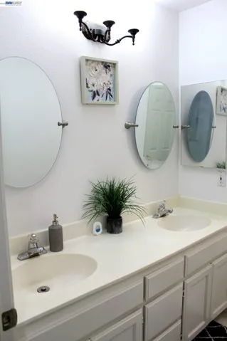 Well-appointed upstairs full bathroom featuring a dual-sink vanity, generous counter space, a shower-over-tub combination, and abundant natural light—designed to comfortably serve the secondary bedrooms and guests.