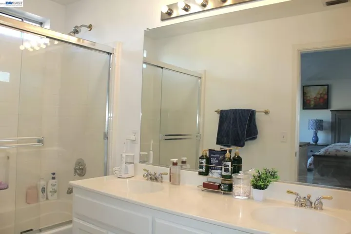 Well-appointed primary bathroom featuring a double vanity, large mirror, glass-enclosed shower, and generous counter space, providing both style and everyday convenience.