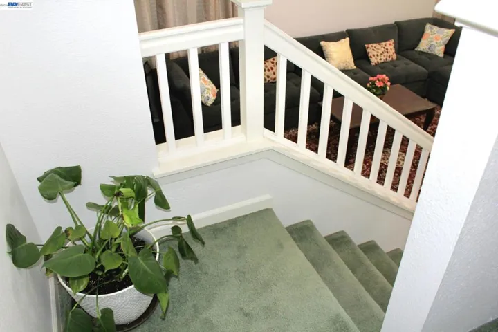 Elegant staircase with open railings overlooks the living room below, bringing in natural light and creating a spacious, open atmosphere throughout the home.