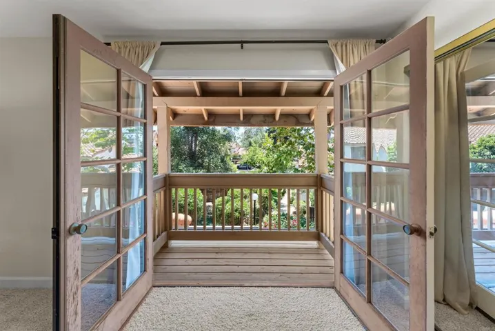 Elegant French doors open to a private covered balcony overlooking lush landscaping.