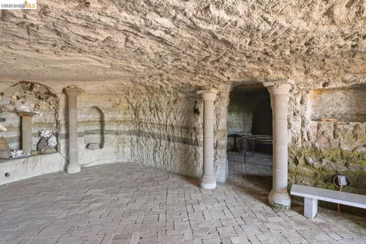 Cave featuring natural stone walls and ceiling, brick-laid flooring, and decorative stone columns