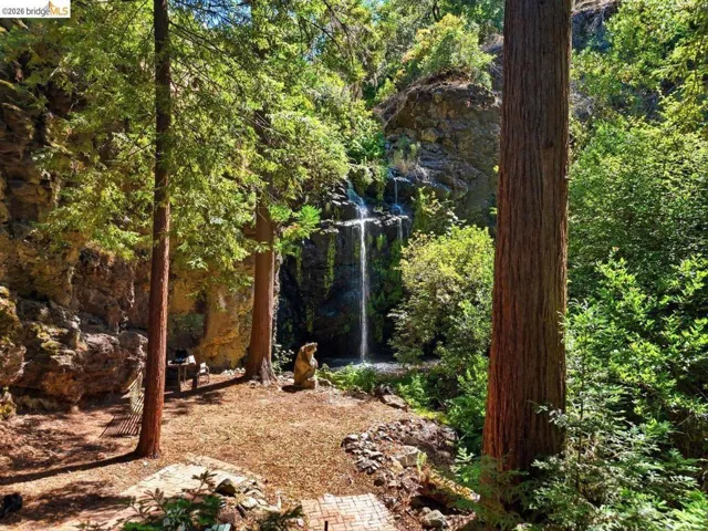 Natural rock face with a cascading waterfall, framed by mature redwood trees