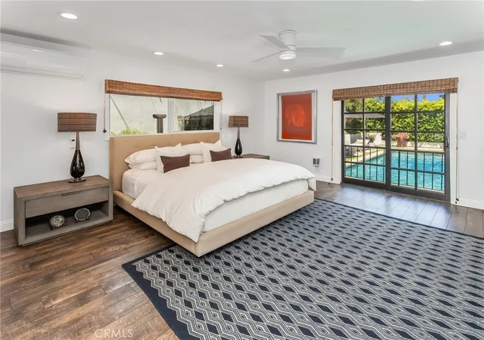 Privately situated, the oversized primary suite offers dual mirrored closets, a newer Lennox mini-split air conditioning system, recessed lighting, a modern ceiling fan, and sliding French doors that open directly to the backyard.