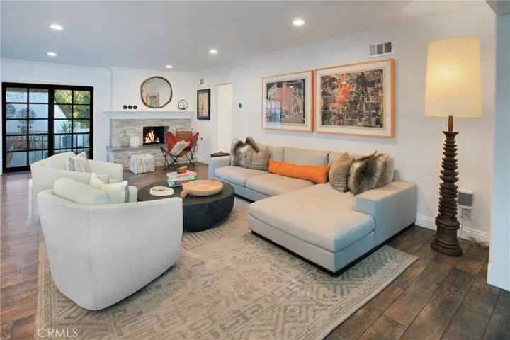 An inviting family room offers a raised-hearth gas fireplace with a designer insert, crown molding, recessed lighting, and beautiful hillside views framed by the surrounding windows.
