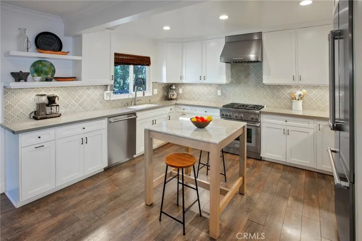 At the heart of the home, the beautifully appointed kitchen pairs custom white soft-closing cabinetry, elegant quartz countertops, a center island, showcase shelving, a full tile backsplash, and Waterdrop filtration with a premium Thermador stainless steel appliance package that includes a commercial-style 5-burner gas range, French door refrigerator/freezer, microwave, warming drawer, dishwasher, and ventilation hood.